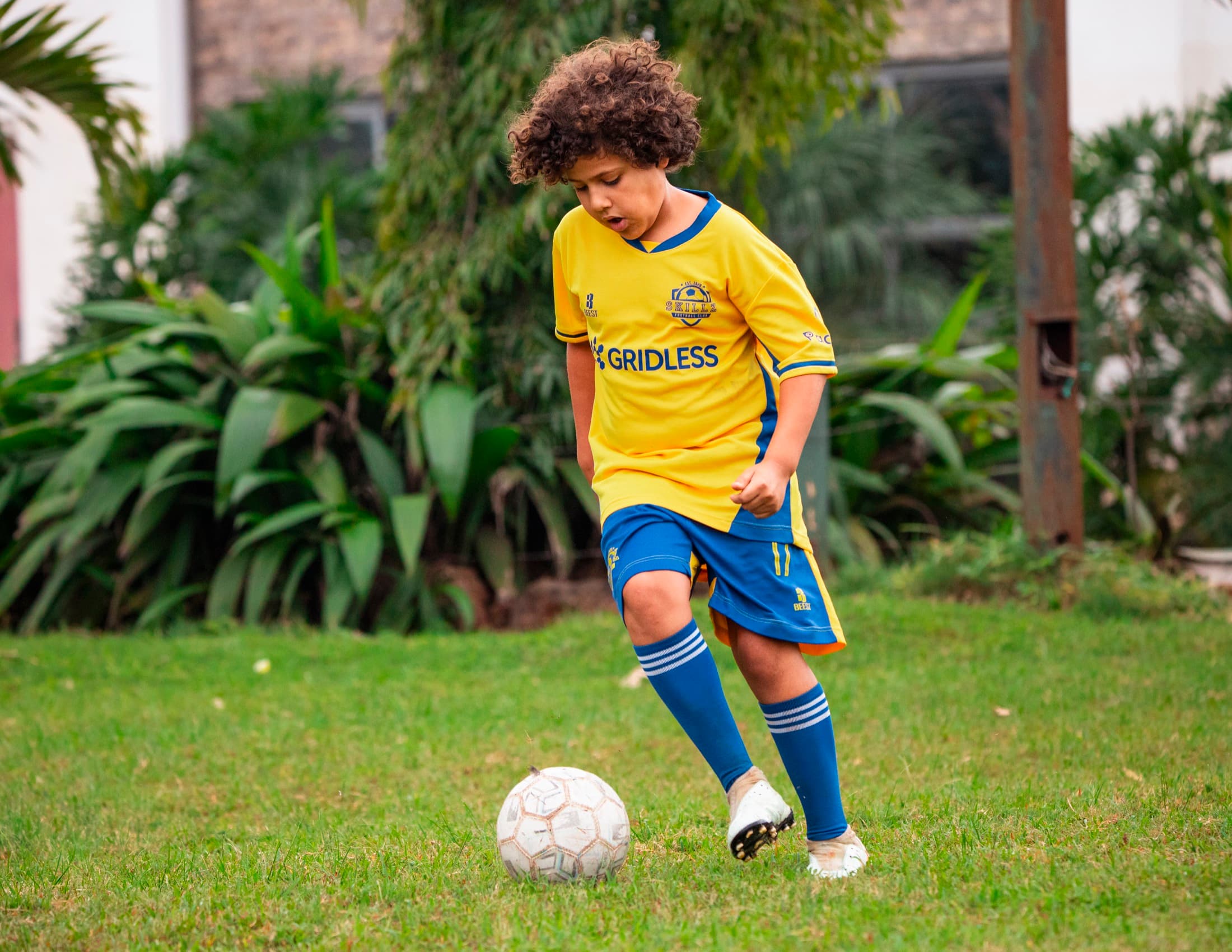 Skillz Academy player in a yellow and blue kit controlling the ball